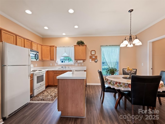 kitchen featuring white appliances, a chandelier, dark wood-style floors, a kitchen island, and ornamental molding