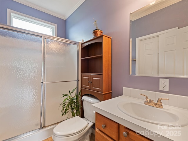 bathroom with a shower stall, toilet, vanity, and crown molding