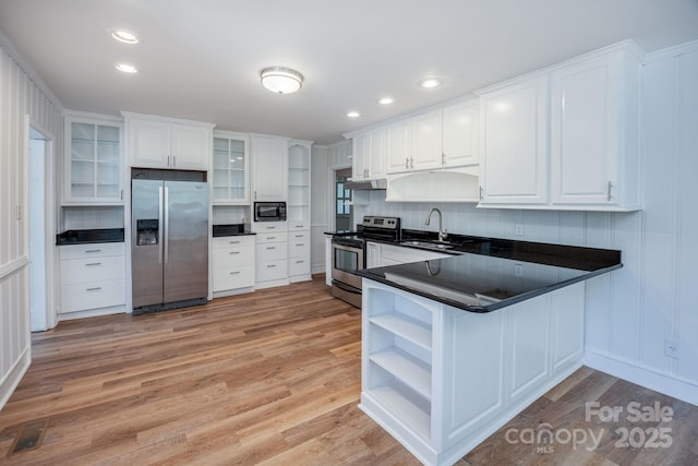 402 Hudson St, Winnsboro, SC 29180 - kitchen with stainless steel appliances, open shelves, dark countertops, a sink, and light wood-style flooring