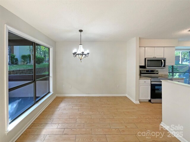 kitchen with white cabinets, a chandelier, a textured ceiling, and appliances with stainless steel finishes