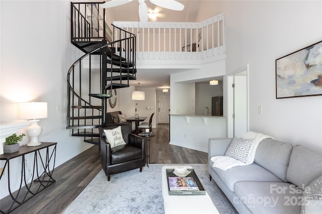 living area featuring wood finished floors, a towering ceiling, and stairs