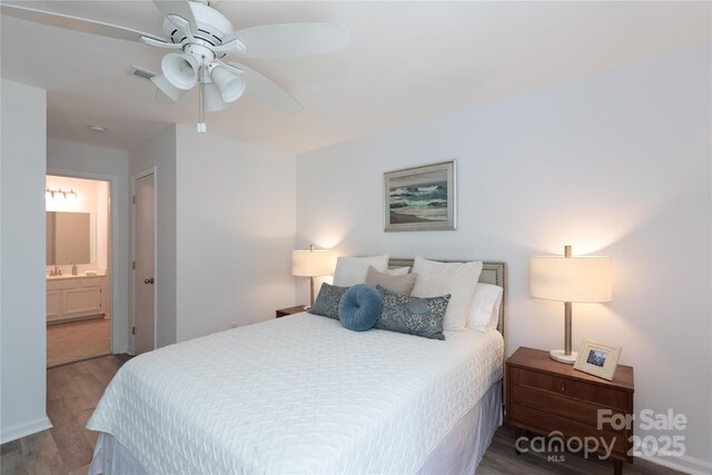 bedroom with a sink, visible vents, a ceiling fan, wood finished floors, and ensuite bath