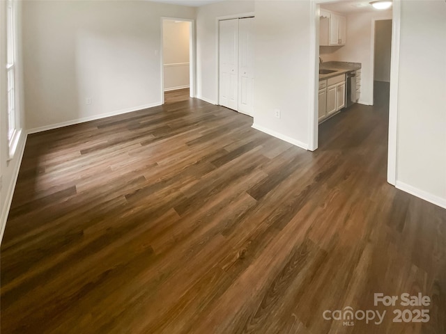 8026 Regent Park Ln, Charlotte, NC 28210 - unfurnished living room with baseboards, dark wood-type flooring, and a sink