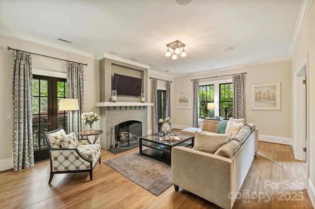 living area with wood finished floors, visible vents, and crown molding