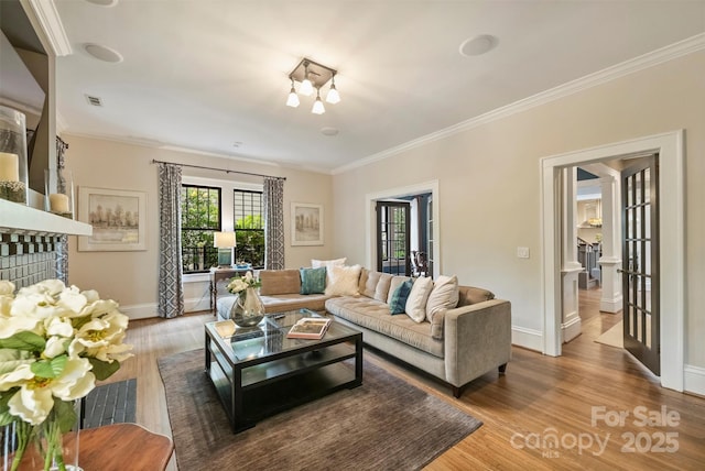 living area featuring baseboards, crown molding, wood finished floors, and visible vents