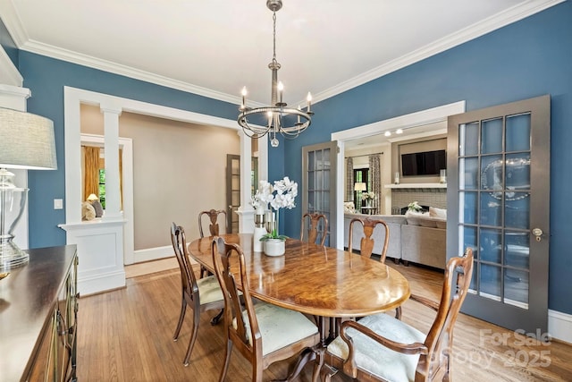 dining area featuring light wood-style flooring, baseboards, a notable chandelier, and crown molding