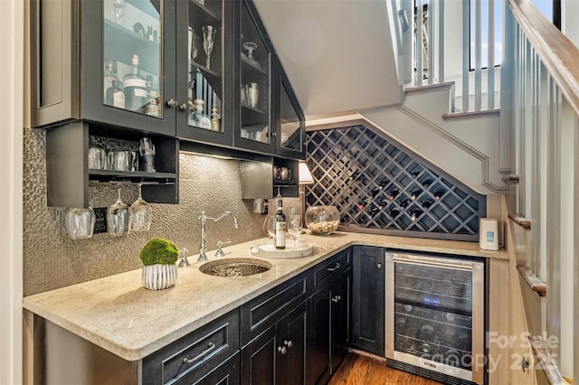 bar featuring wood finished floors, a sink, backsplash, wet bar, and wine cooler