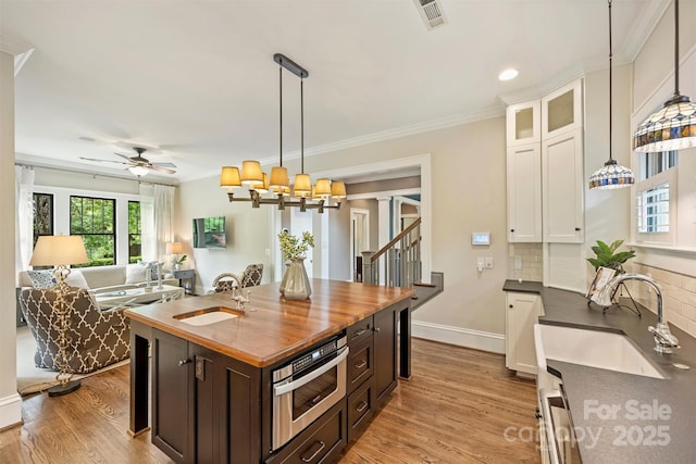 kitchen with visible vents, a sink, wooden counters, and white cabinetry