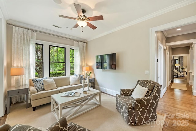 living area with wood finished floors, visible vents, crown molding, baseboards, and ceiling fan