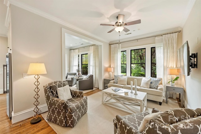 living room with crown molding, wood finished floors, ceiling fan, baseboards, and visible vents