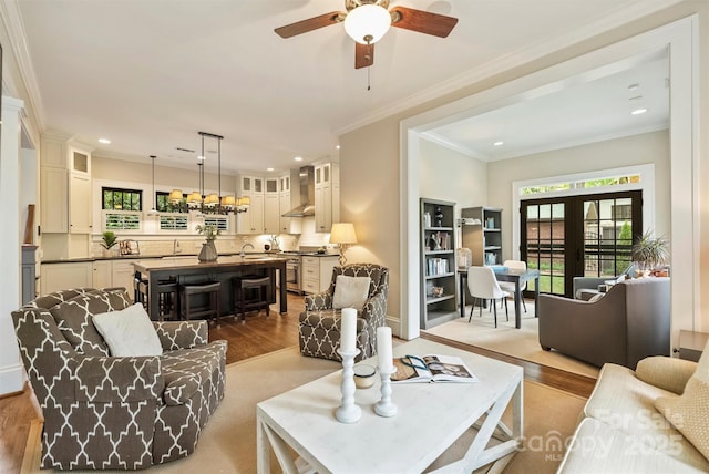 living area with recessed lighting, wood finished floors, crown molding, and ceiling fan
