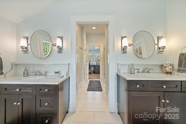 full bathroom featuring two vanities, tile patterned floors, a sink, and baseboards