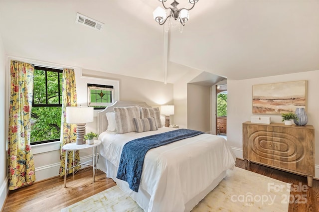 bedroom featuring vaulted ceiling, wood finished floors, visible vents, and multiple windows