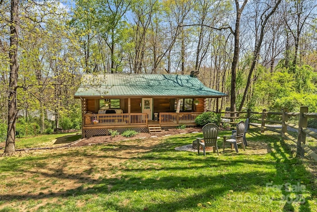 rear view of property with a chimney, fence, a yard, covered porch, and metal roof