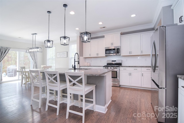 2014 Burton Point Ct, Waxhaw, NC 28173 - kitchen with stainless steel appliances, ornamental molding, wood finished floors, backsplash, and white cabinetry