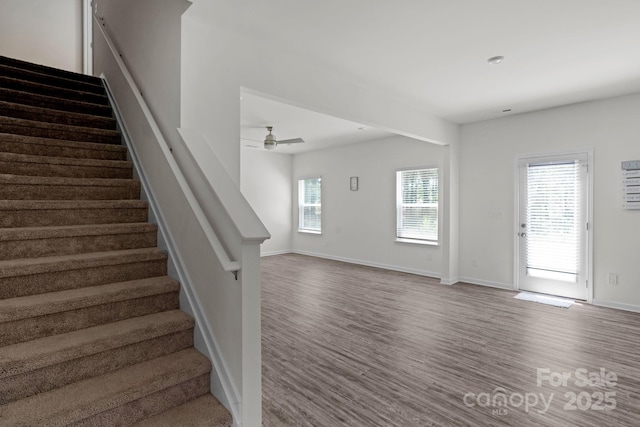 stairway featuring baseboards, wood finished floors, and ceiling fan