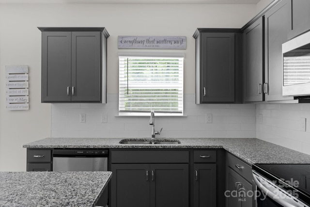 kitchen featuring light stone counters, decorative backsplash, stainless steel appliances, and a sink