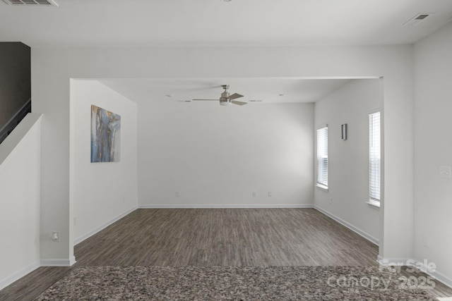 spare room with wood finished floors, visible vents, and baseboards
