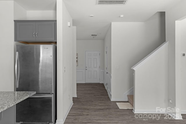 corridor with baseboards, visible vents, stairway, and dark wood-style flooring