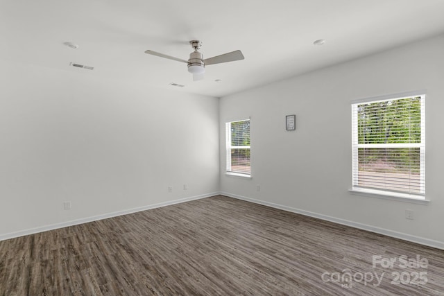 unfurnished room with ceiling fan, a healthy amount of sunlight, baseboards, and dark wood-style flooring
