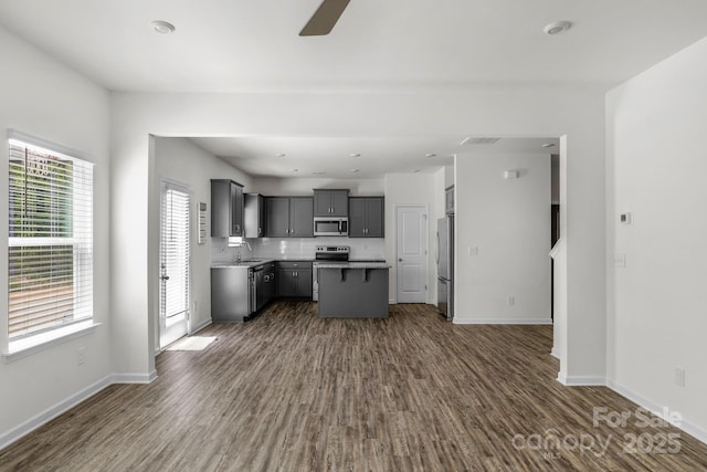 kitchen with dark wood-style floors, stainless steel appliances, a ceiling fan, gray cabinets, and a sink