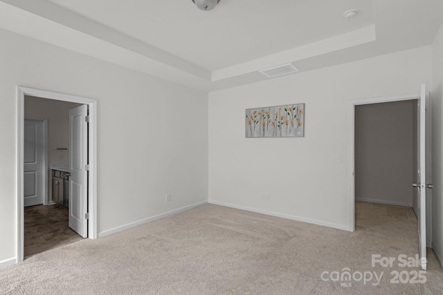 unfurnished bedroom featuring visible vents, baseboards, carpet flooring, and a raised ceiling