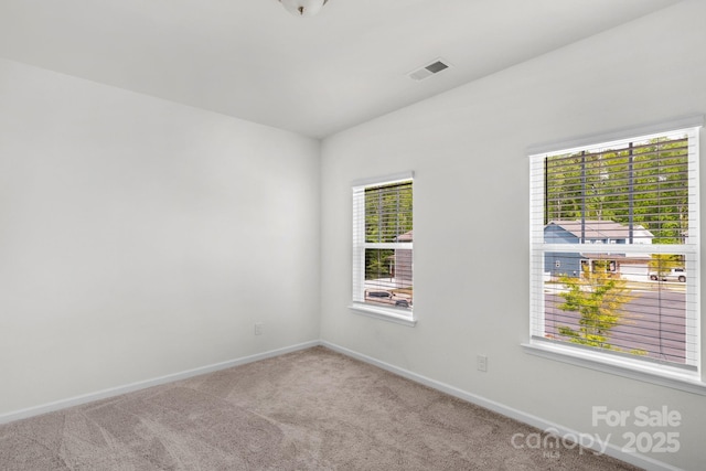 carpeted empty room with plenty of natural light, baseboards, and visible vents