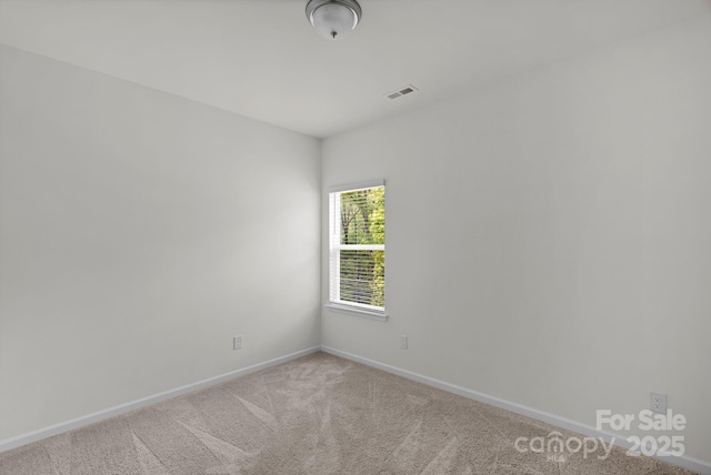 carpeted empty room featuring baseboards and visible vents