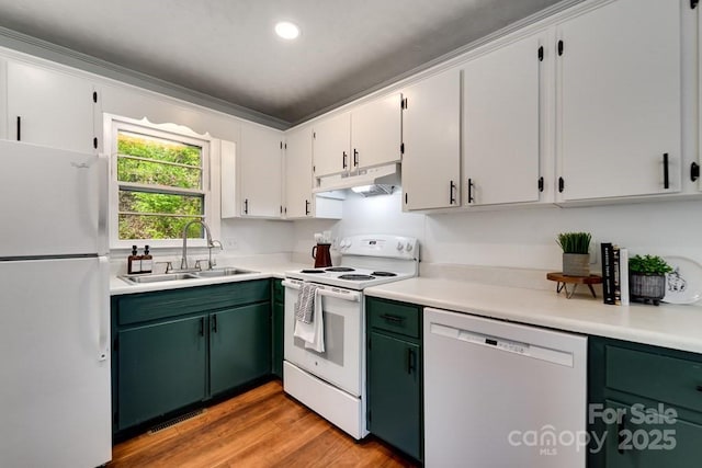 kitchen featuring white appliances, light countertops, under cabinet range hood, a sink, and light wood finished floors