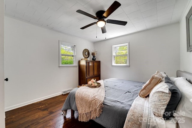 bedroom featuring a ceiling fan, baseboards, dark wood-style floors, and multiple windows