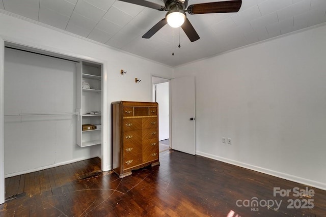unfurnished bedroom featuring a closet, ornamental molding, wood finished floors, baseboards, and a ceiling fan