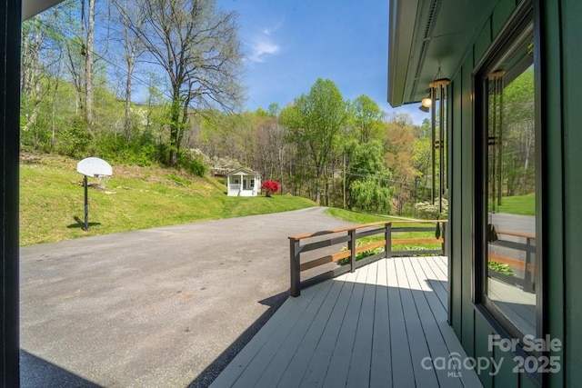 wooden deck featuring a lawn and a forest view