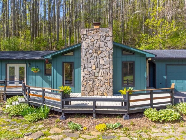 view of side of home featuring french doors, a wooden deck, board and batten siding, and a garage