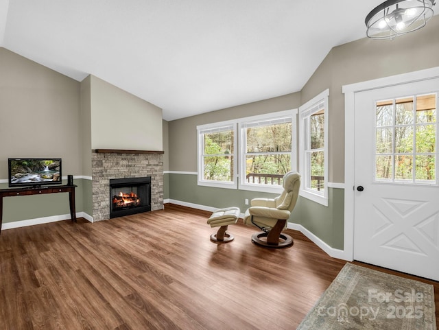 living area with baseboards, wood finished floors, lofted ceiling, and a fireplace