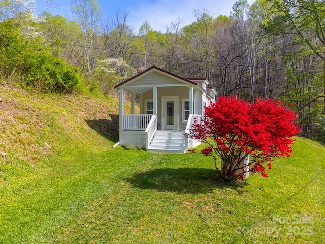 view of outdoor structure with a view of trees and covered porch