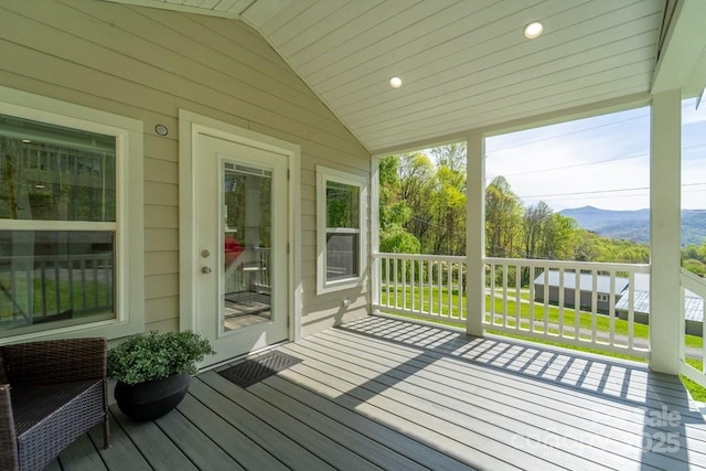 wooden deck with a mountain view and a yard