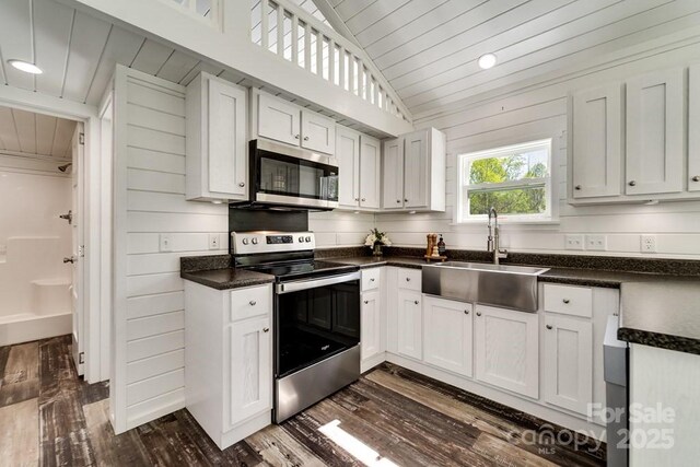 kitchen featuring wood ceiling, dark countertops, a sink, dark wood-style floors, and stainless steel appliances