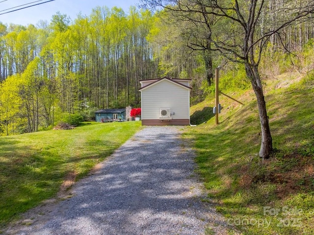 view of property exterior featuring a yard, driveway, and a wooded view