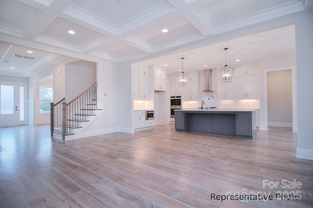 unfurnished living room with stairs, beamed ceiling, visible vents, and light wood-style flooring