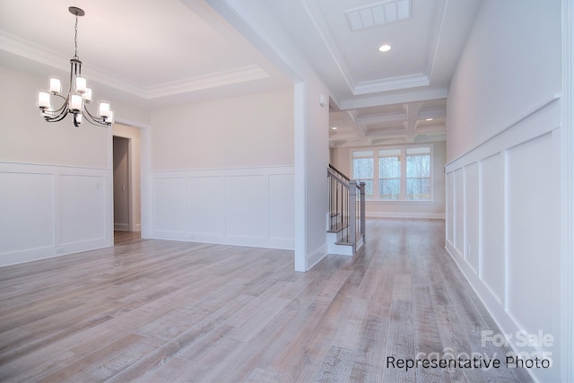 foyer with visible vents, a decorative wall, stairway, light wood-type flooring, and a chandelier
