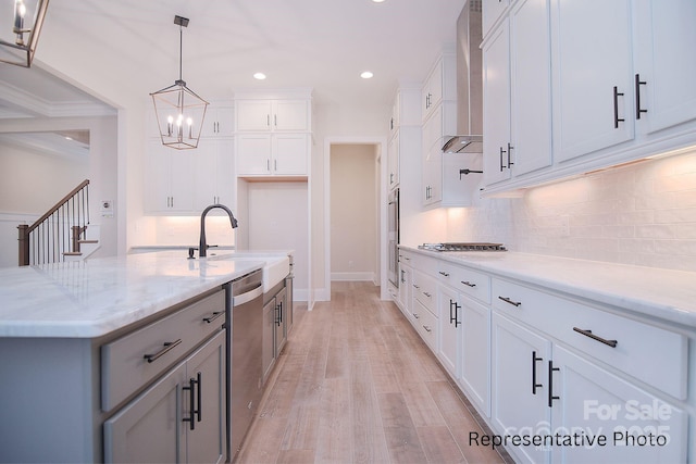 kitchen with wall chimney range hood, a sink, dishwasher, backsplash, and pendant lighting