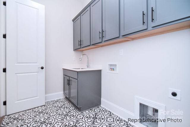 clothes washing area with a sink, baseboards, hookup for an electric dryer, and cabinet space