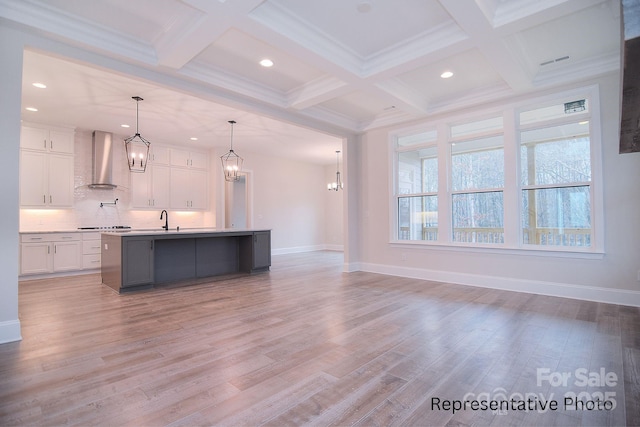 kitchen with white cabinetry, a chandelier, beam ceiling, and wall chimney exhaust hood