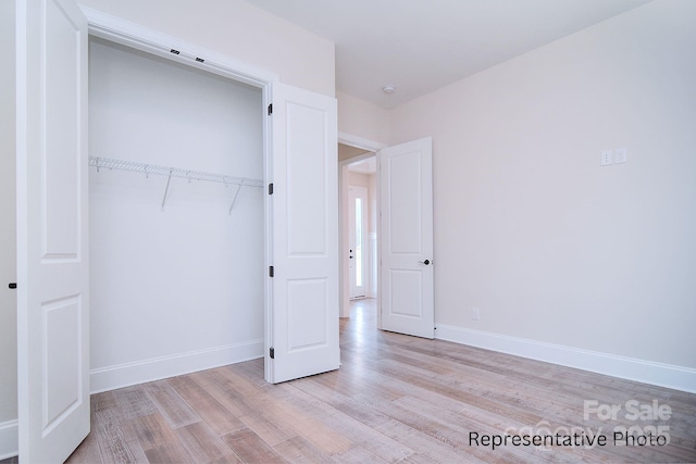 unfurnished bedroom featuring baseboards, a closet, and wood finished floors