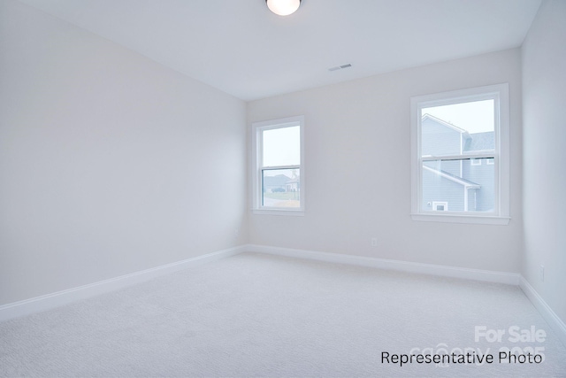 unfurnished room featuring baseboards, plenty of natural light, visible vents, and light colored carpet