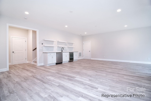 unfurnished living room featuring wet bar, baseboards, light wood finished floors, beverage cooler, and recessed lighting