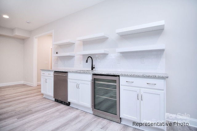 bar featuring a sink, light wood-style flooring, backsplash, and beverage cooler