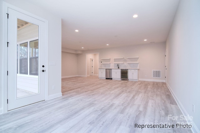 unfurnished living room featuring light wood-style flooring, recessed lighting, beverage cooler, and visible vents