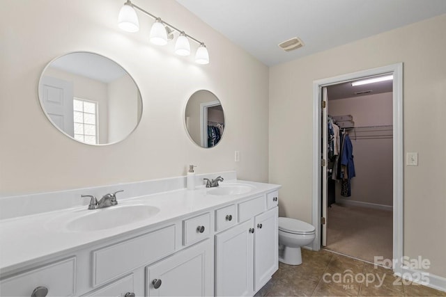 bathroom with visible vents, a sink, double vanity, and toilet