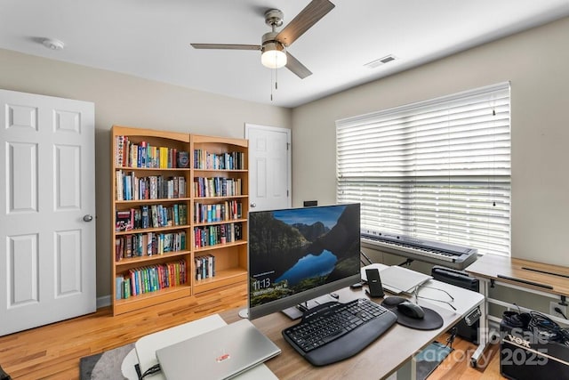 office area with a ceiling fan, visible vents, and wood finished floors